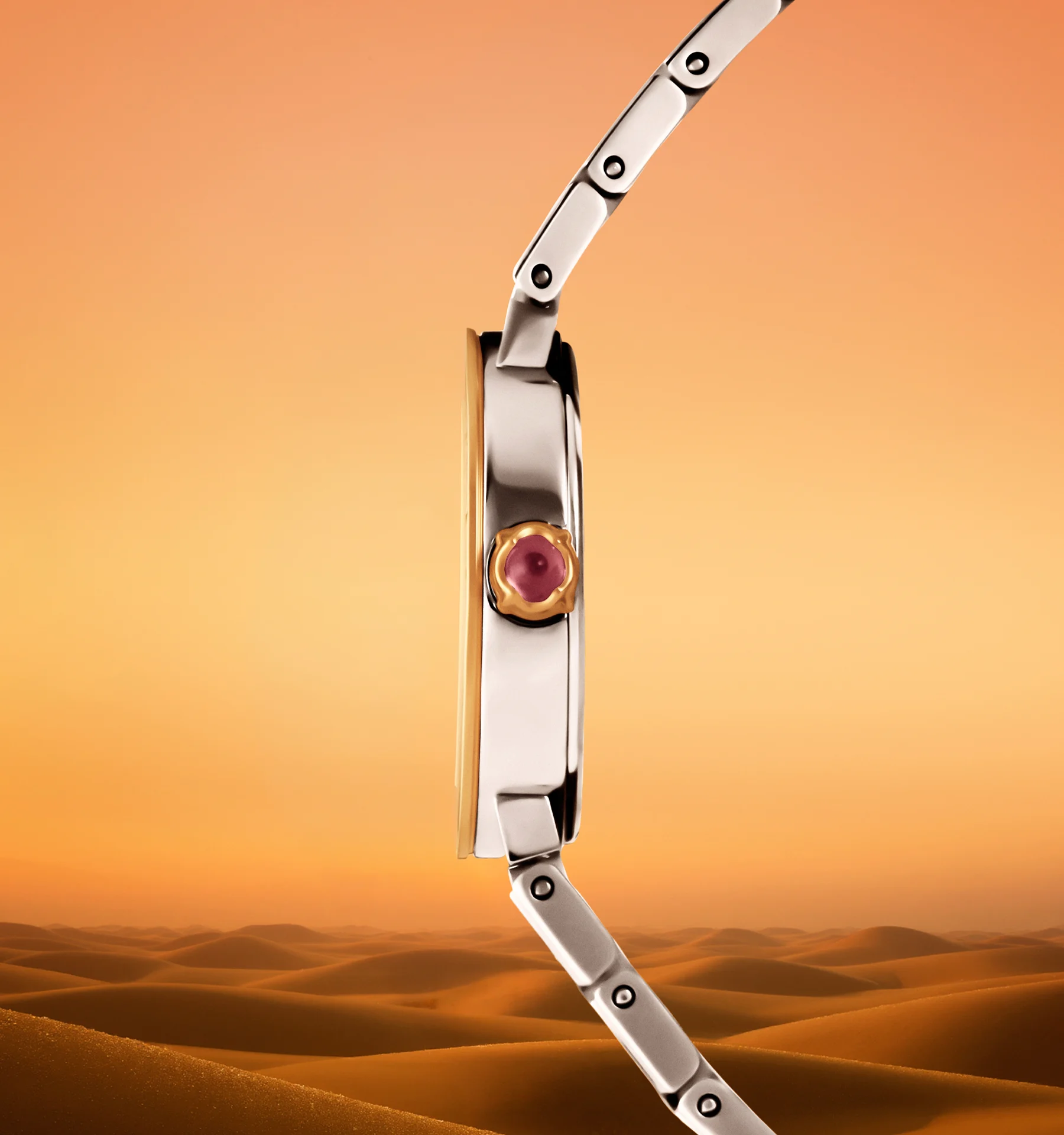 Side profile of the Bvlgari Bvlgari Kuwait Limited Edition watch with a rubellite cabochon crown, set against Kuwait's desert dunes at dusk